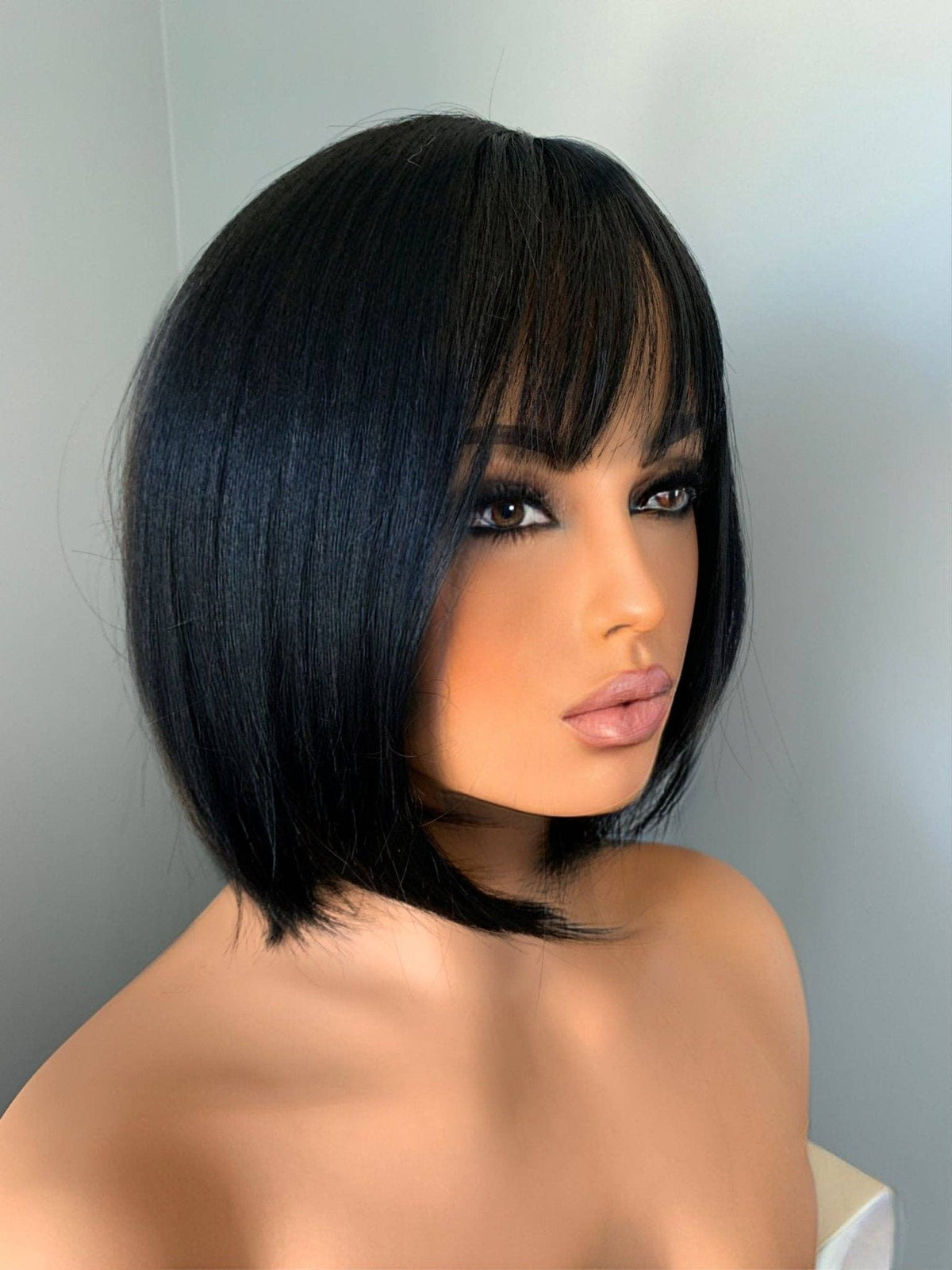 Person with a stylish black bob haircut against a plain background