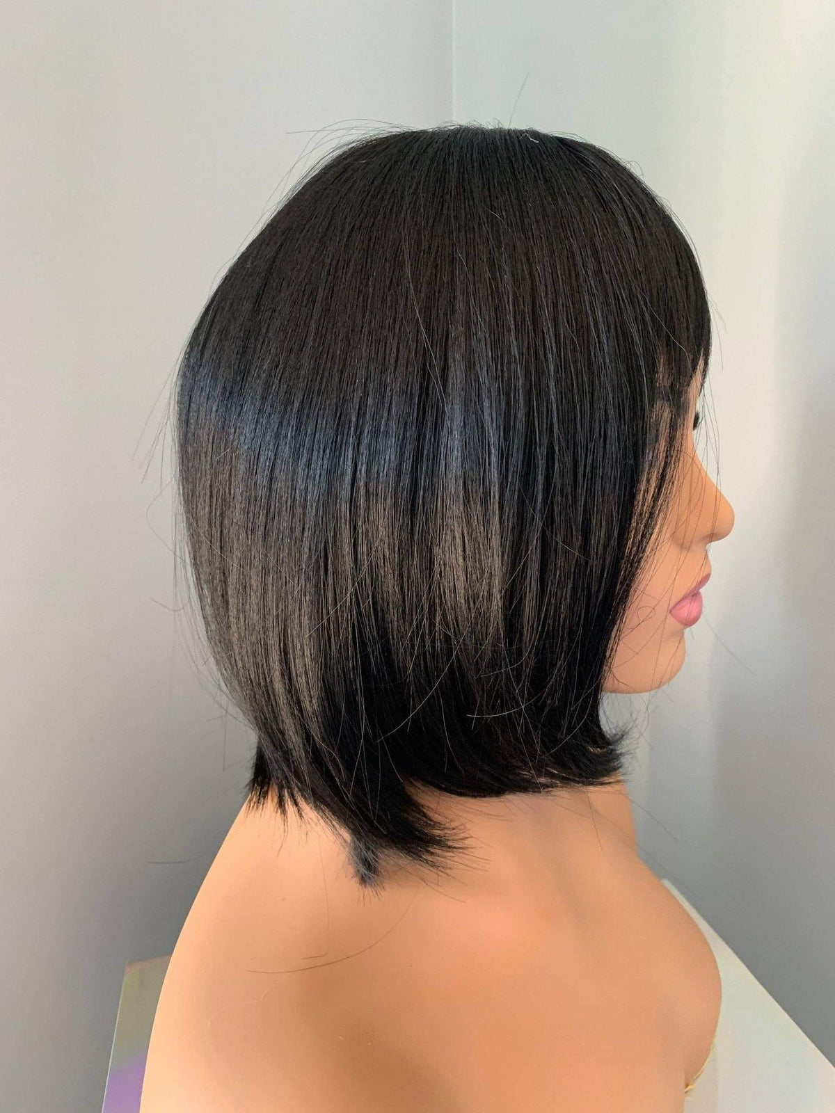 Person with a stylish black bob haircut against a neutral background