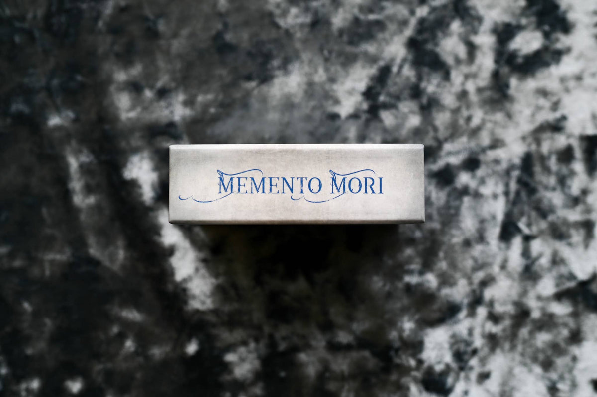 Memento Mori Cards displayed on a textured dark surface, showcasing their elegant design and thoughtful messaging.