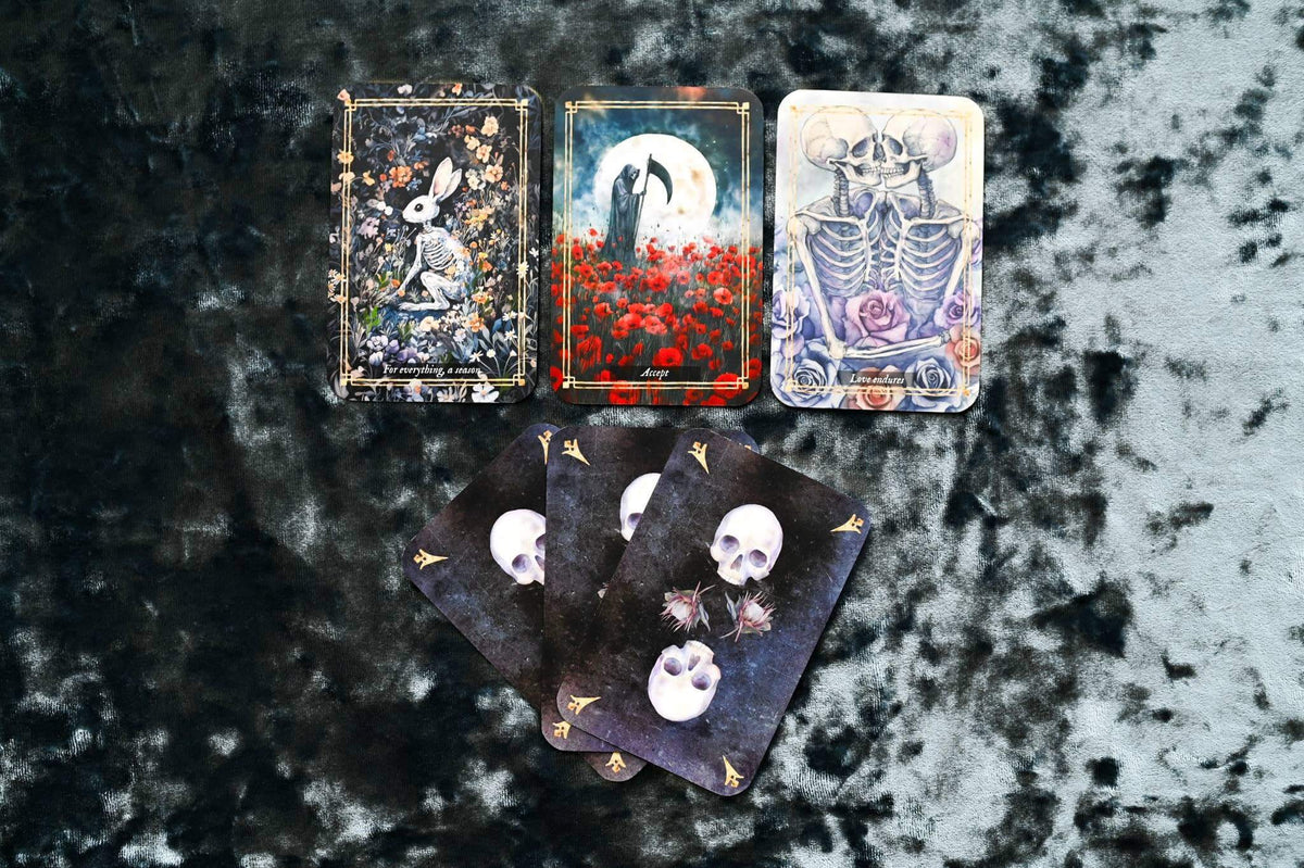 Memento Mori Cards displayed on dark fabric, featuring artwork symbolizing mindfulness and the appreciation of life.
