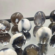 Black and white marbled beads on a reflective surface