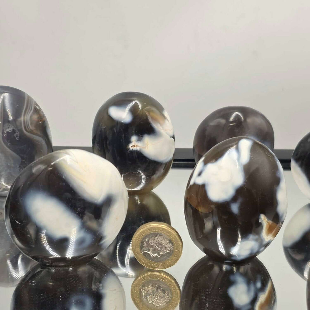 Black and white marbled beads on a reflective surface with a light gray background
