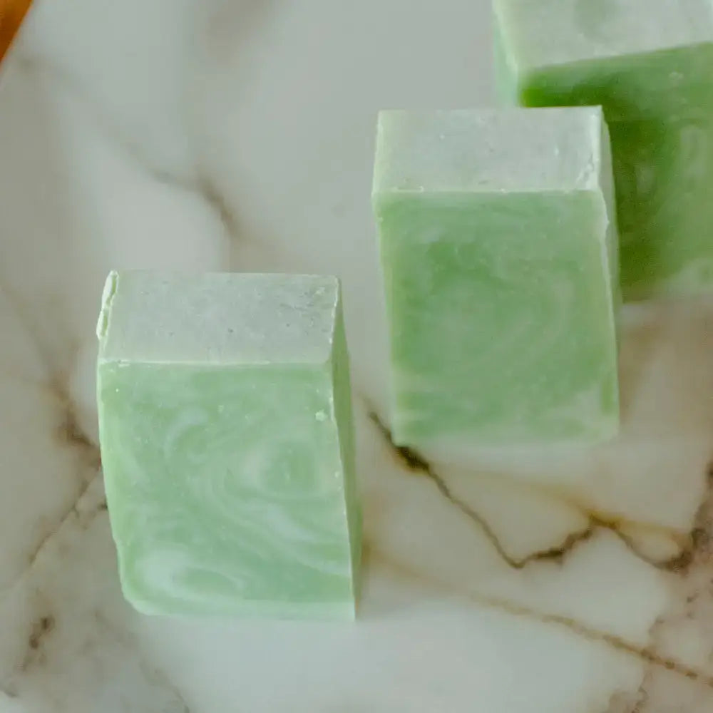 Three green soap bars on a marble surface