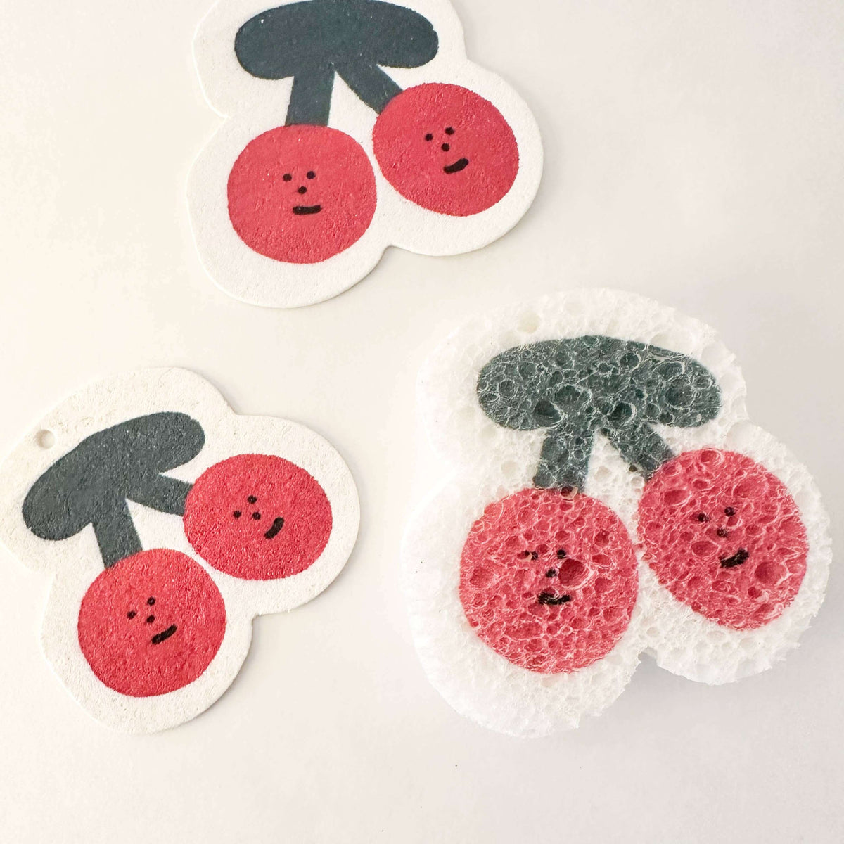 Two cherry-themed sponges on a white background