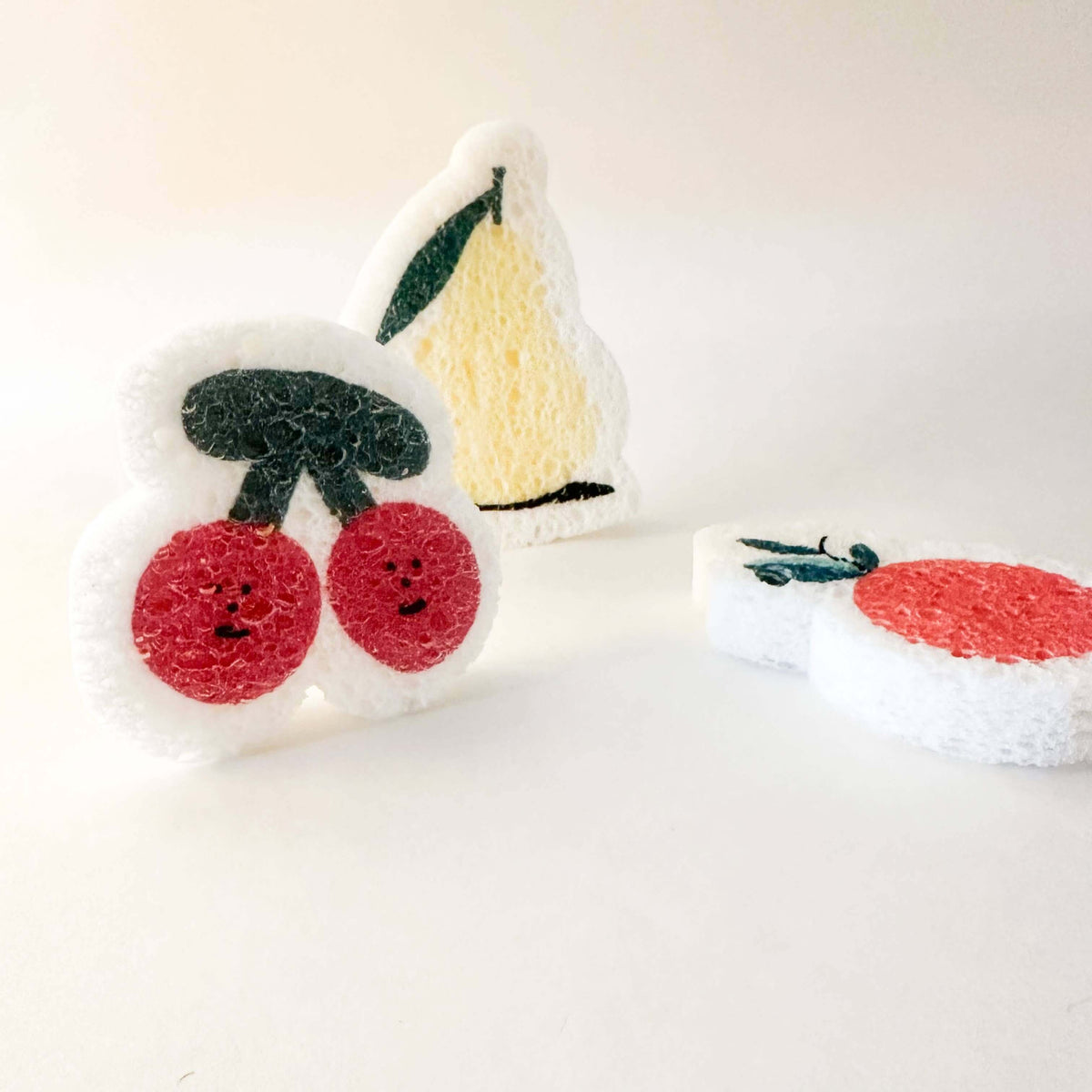 Two plush toys resembling a cherry and a slice of cake on a white background