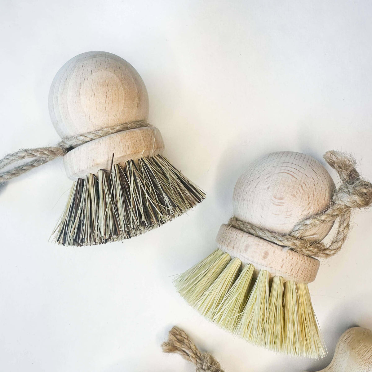Two wooden ball tassels with natural fibers on a white background