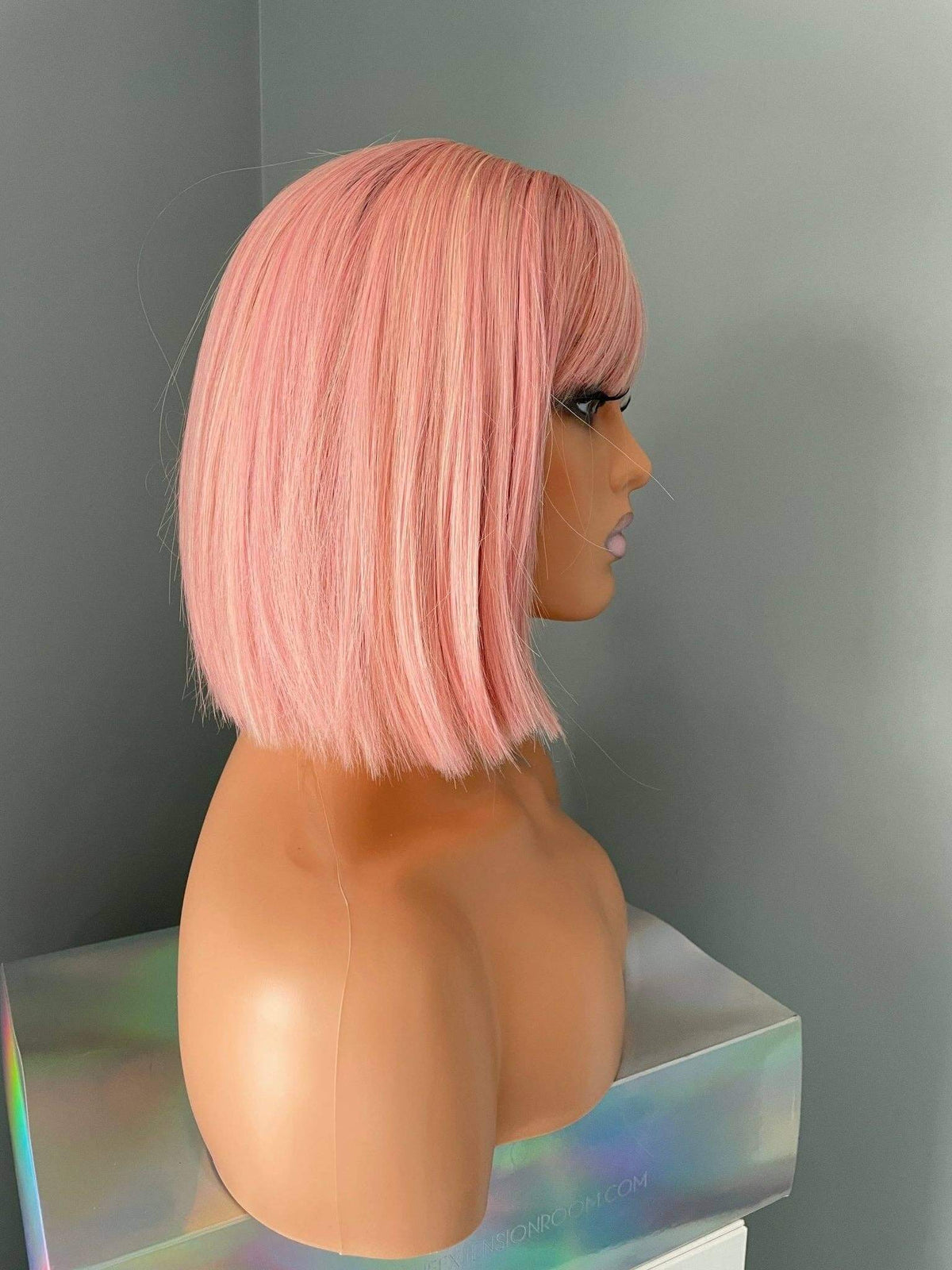 Profile view of a Nia Short Baby Pink Bob Wig, showcasing soft pastel pink tones and full bangs.