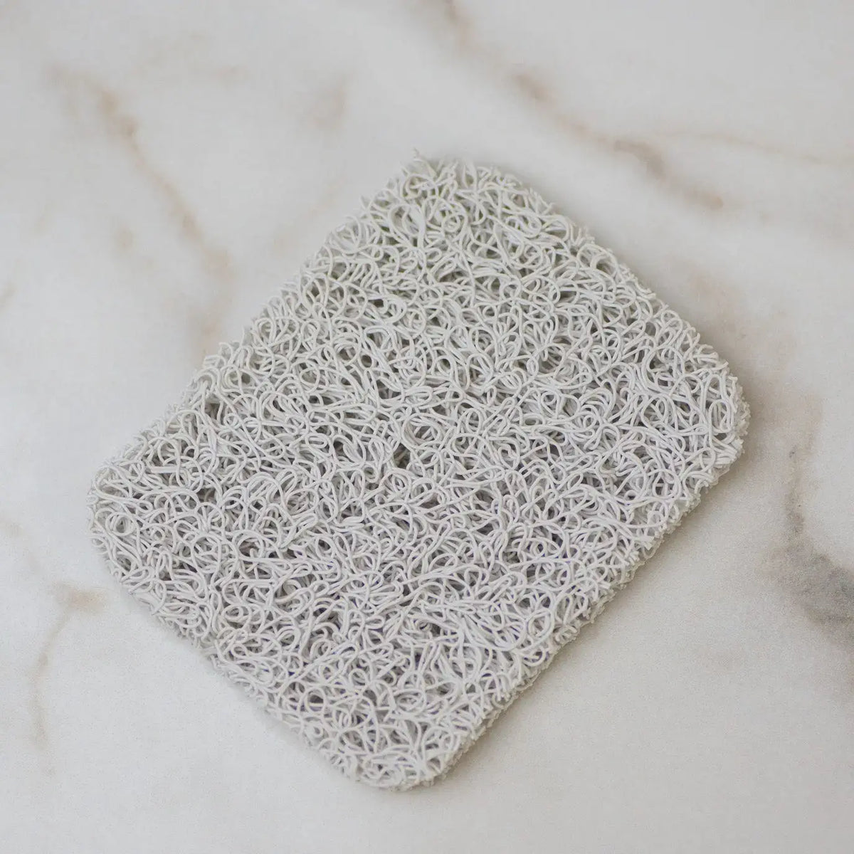 Square white lace doily on a marble surface