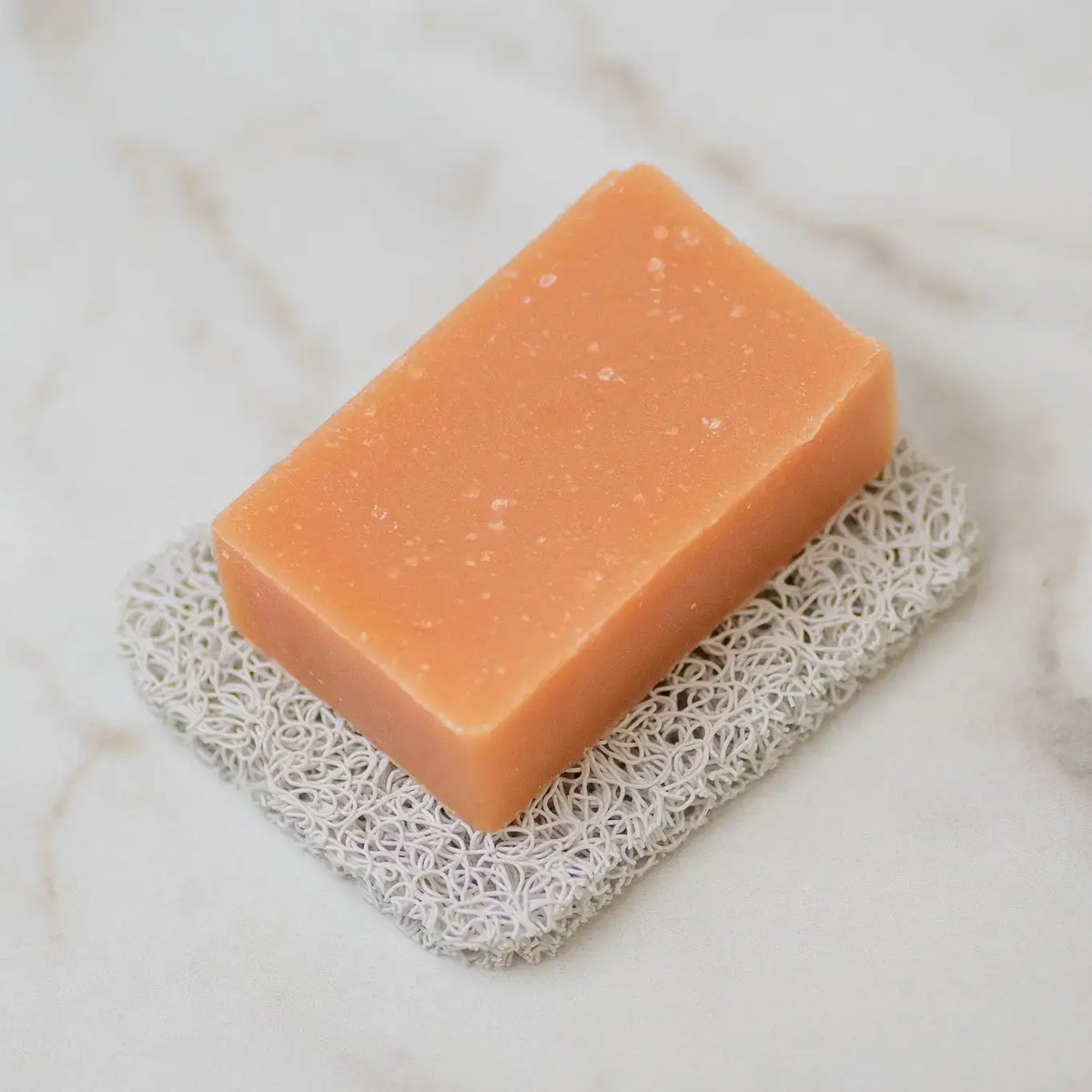 Orange bar of soap on a textured white surface