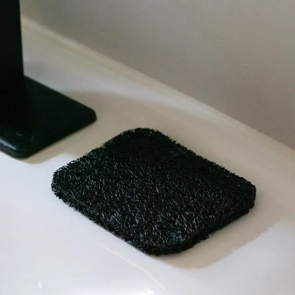 Black scrubber on a white surface with a neutral background