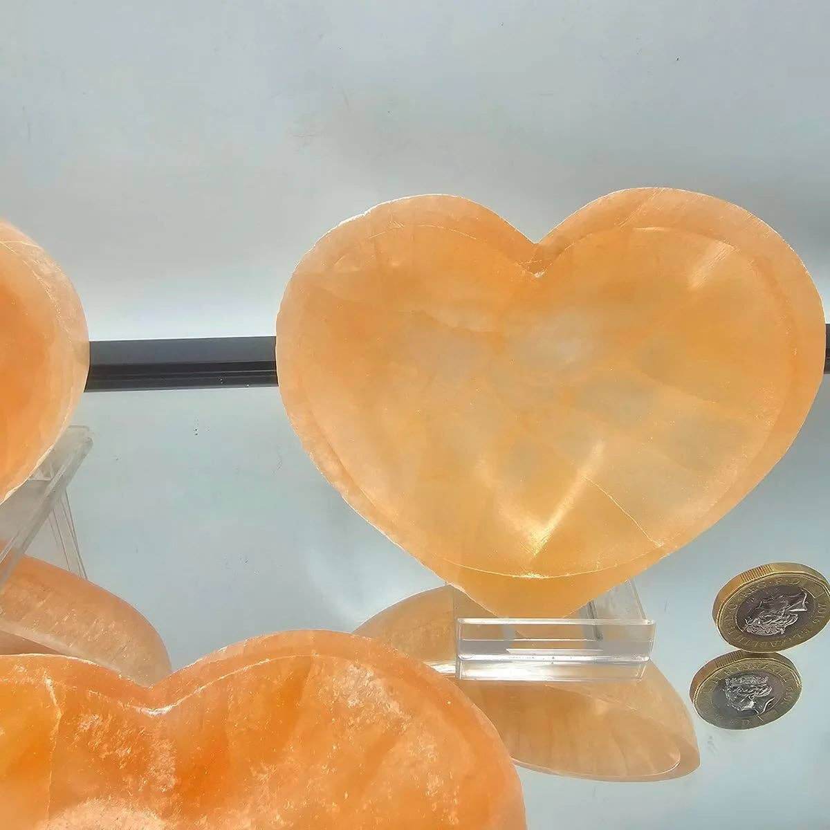 Heart-shaped orange stone on a clear stand with a light gray background