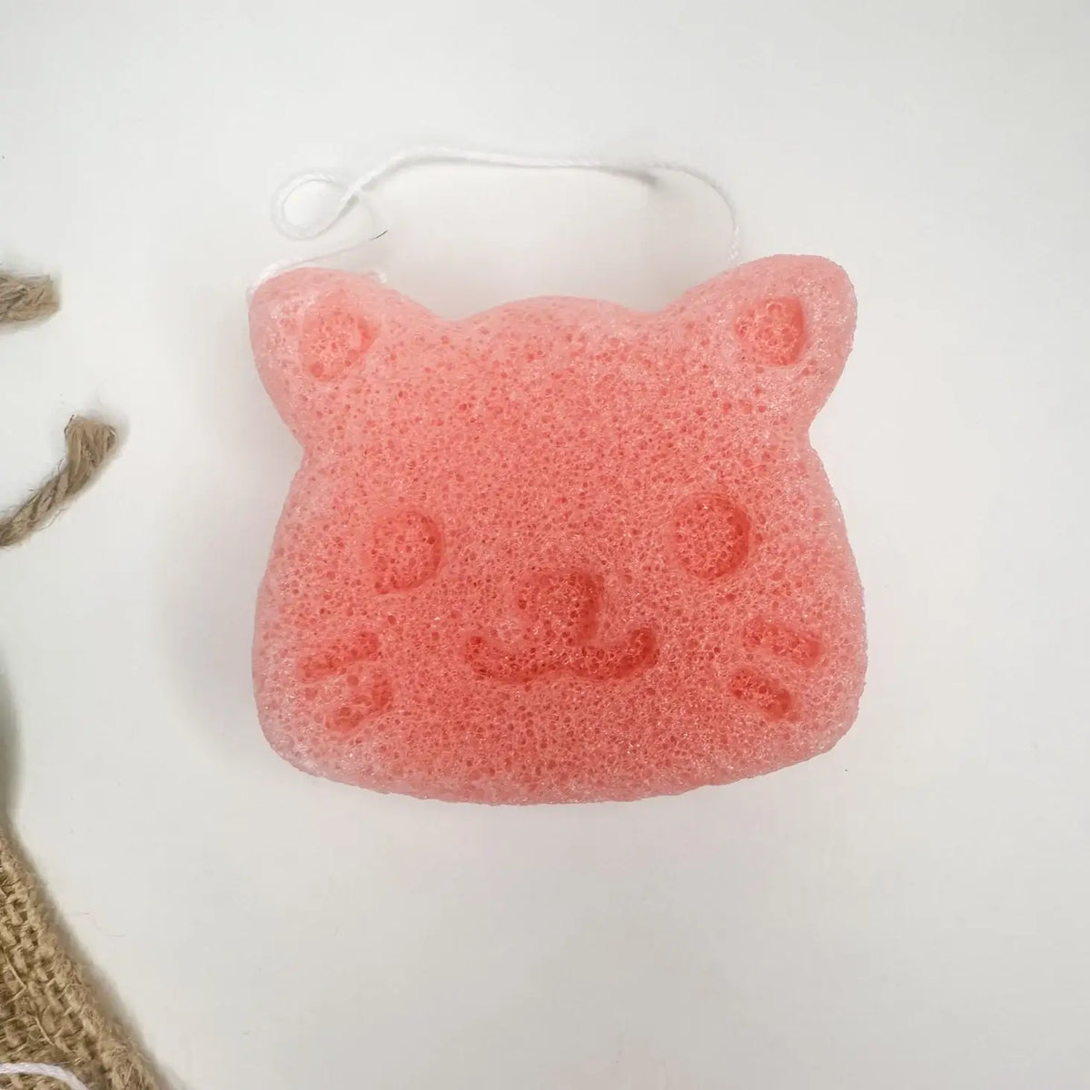 Pink cat-shaped sponge on a white background