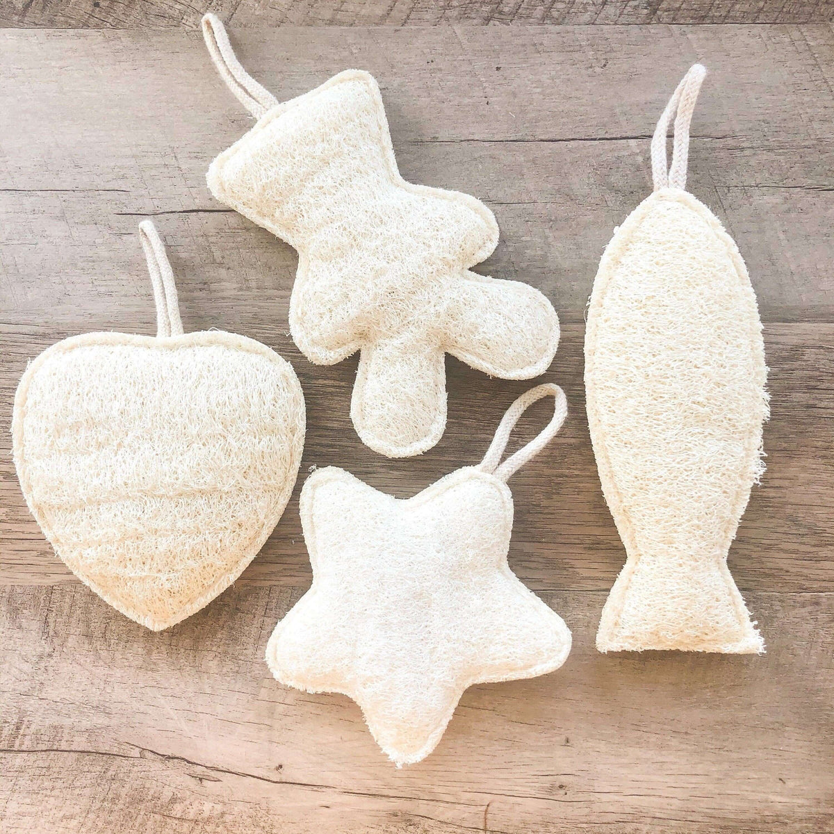 Set of four textured bath bombs shaped like a heart, star, and fish on a wooden surface.
