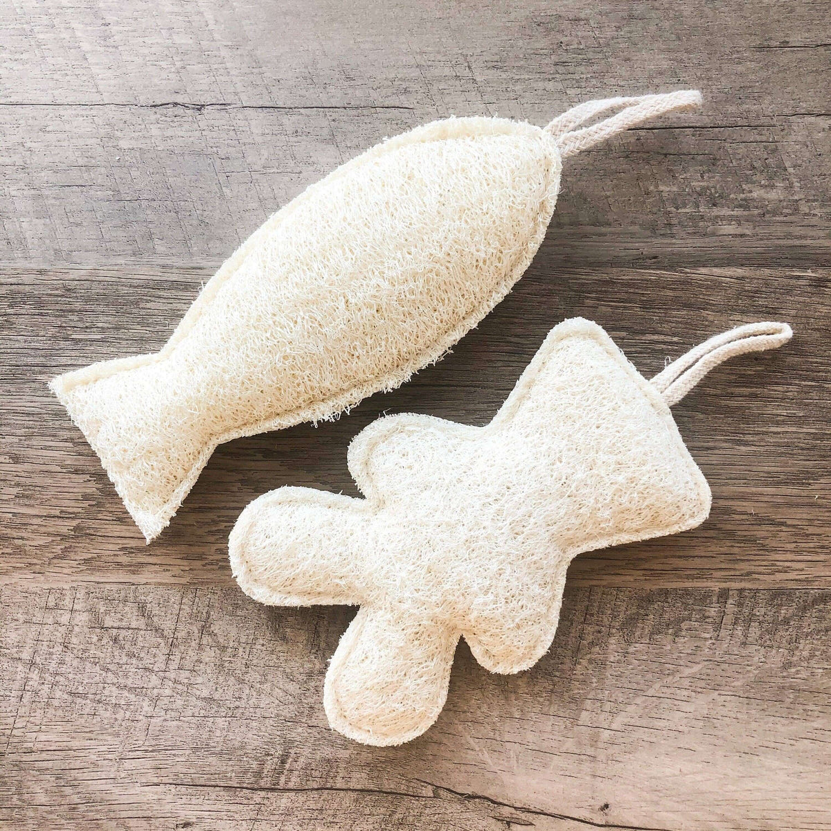 Two textured, beige bath pouf toys on a wooden surface