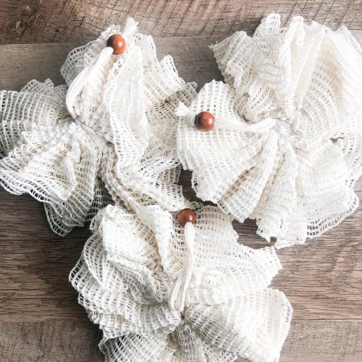 Decorative wreath made of white mesh with wooden beads on a wooden surface