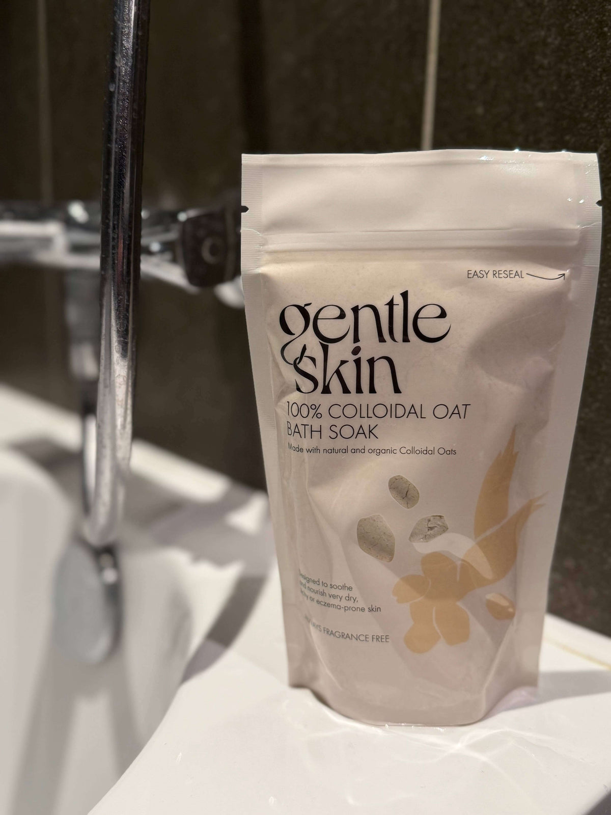 100% Organic Colloidal Oat Bath Soak package next to a bathtub faucet for soothing skin care.