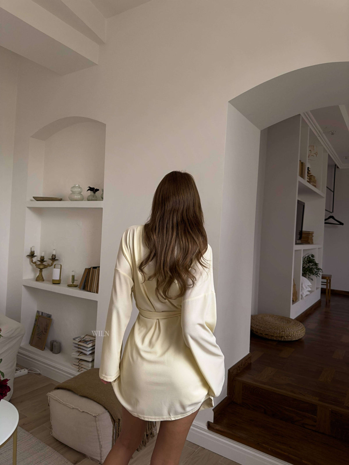 Woman wearing PEACE 3 Piece Lounge Set cream robe, showing relaxed back view in a stylish home.
