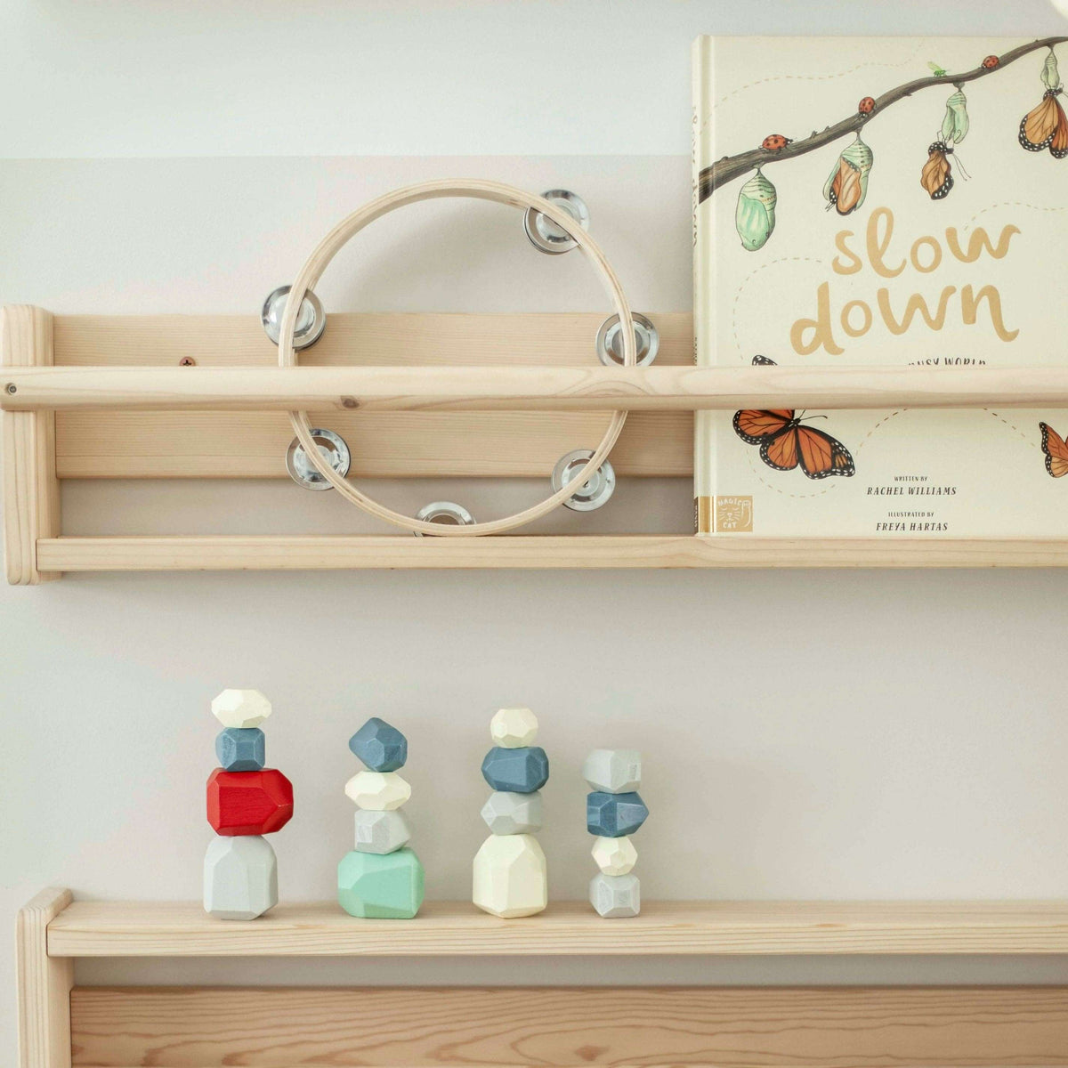 Wooden shelves with toys and a book titled 'slow down' on a white wall.