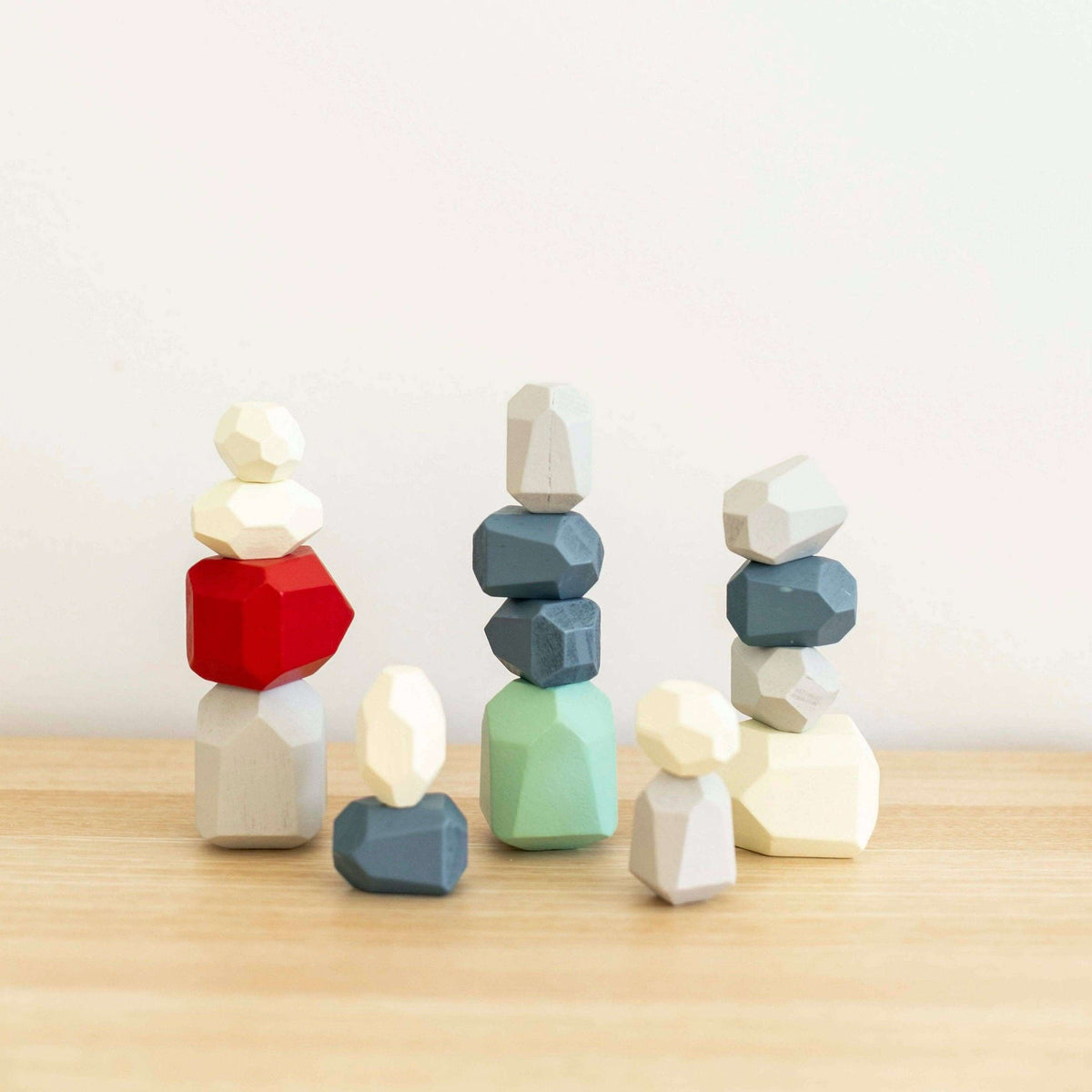 Colorful geometric stone sculptures on a wooden surface with a light background