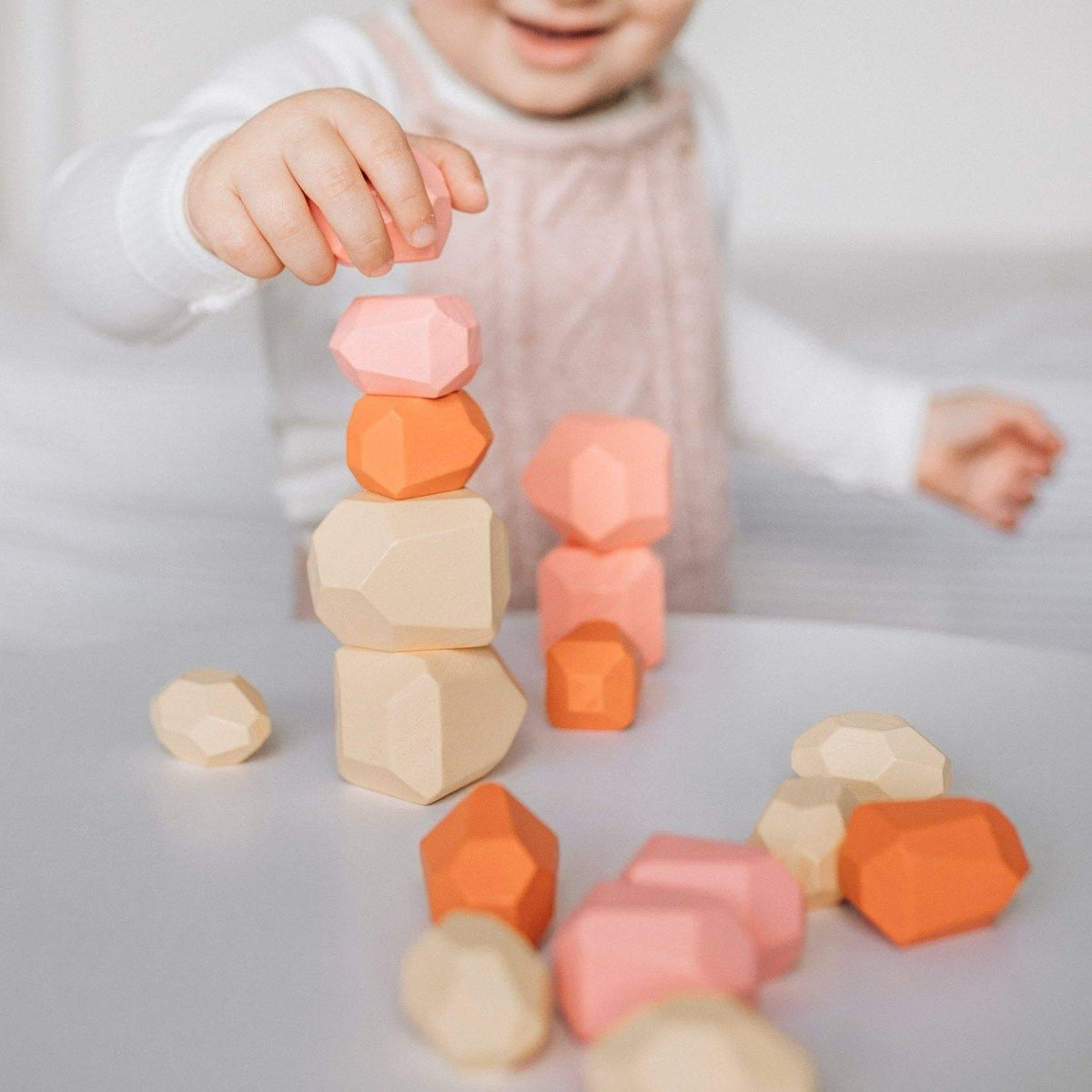 Child playing with colorful geometric wooden blocks on a light surface