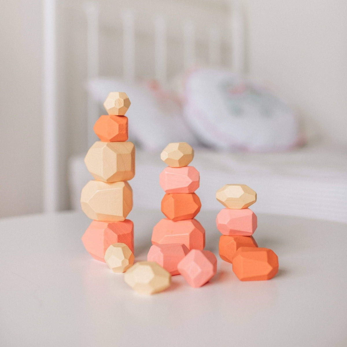 Stacks of colorful geometric wooden blocks on a white surface with a blurred background