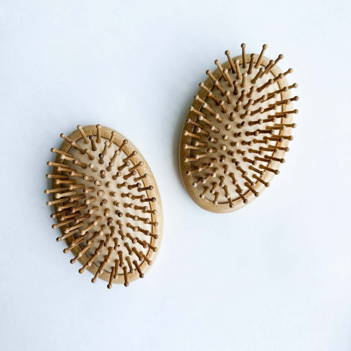 Two wooden hairbrushes on a light blue background