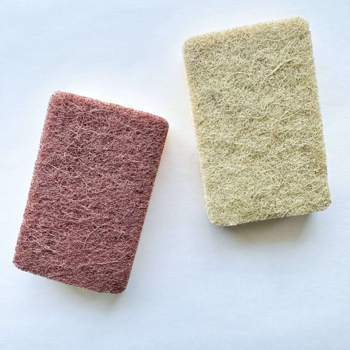 Two scrubbing sponges, one red and one beige, on a white background