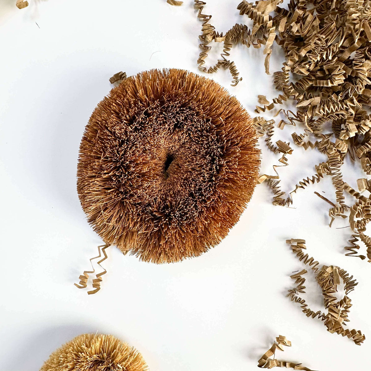 Brown decorative pom-pom with tinsel on a white background