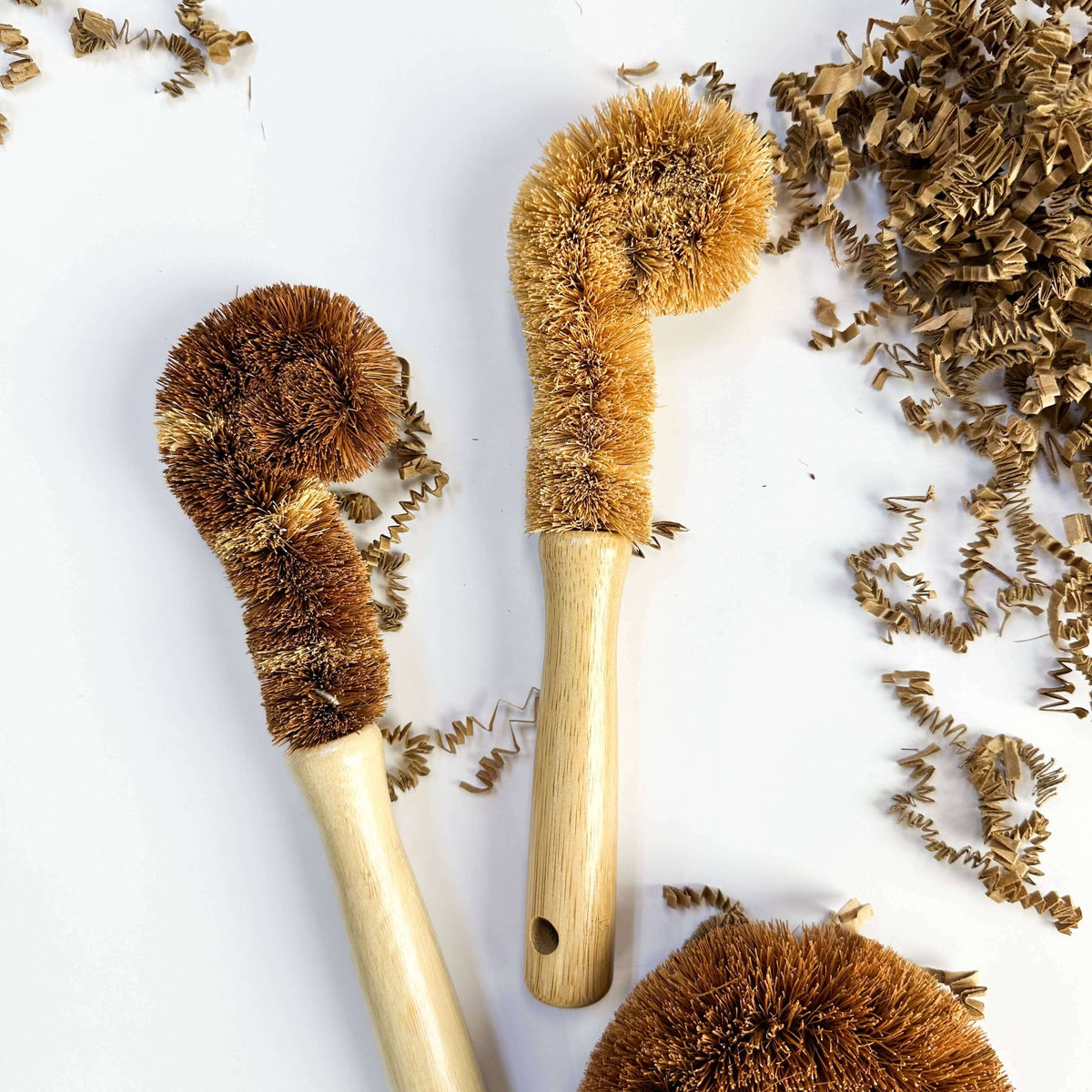 Three natural bristle brushes with wooden handles on a white background.