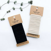 Black and white eco-friendly hair ties on cardboard cards with 'Plastic-Free' and 'Eco-Friendly' labels.