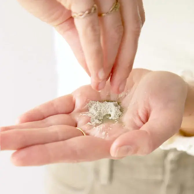 Hands pouring herbal powder cleanser in palm for deep cleansing and detoxifying skin.