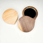 Wooden compact mirror with two different wood finishes on a white background