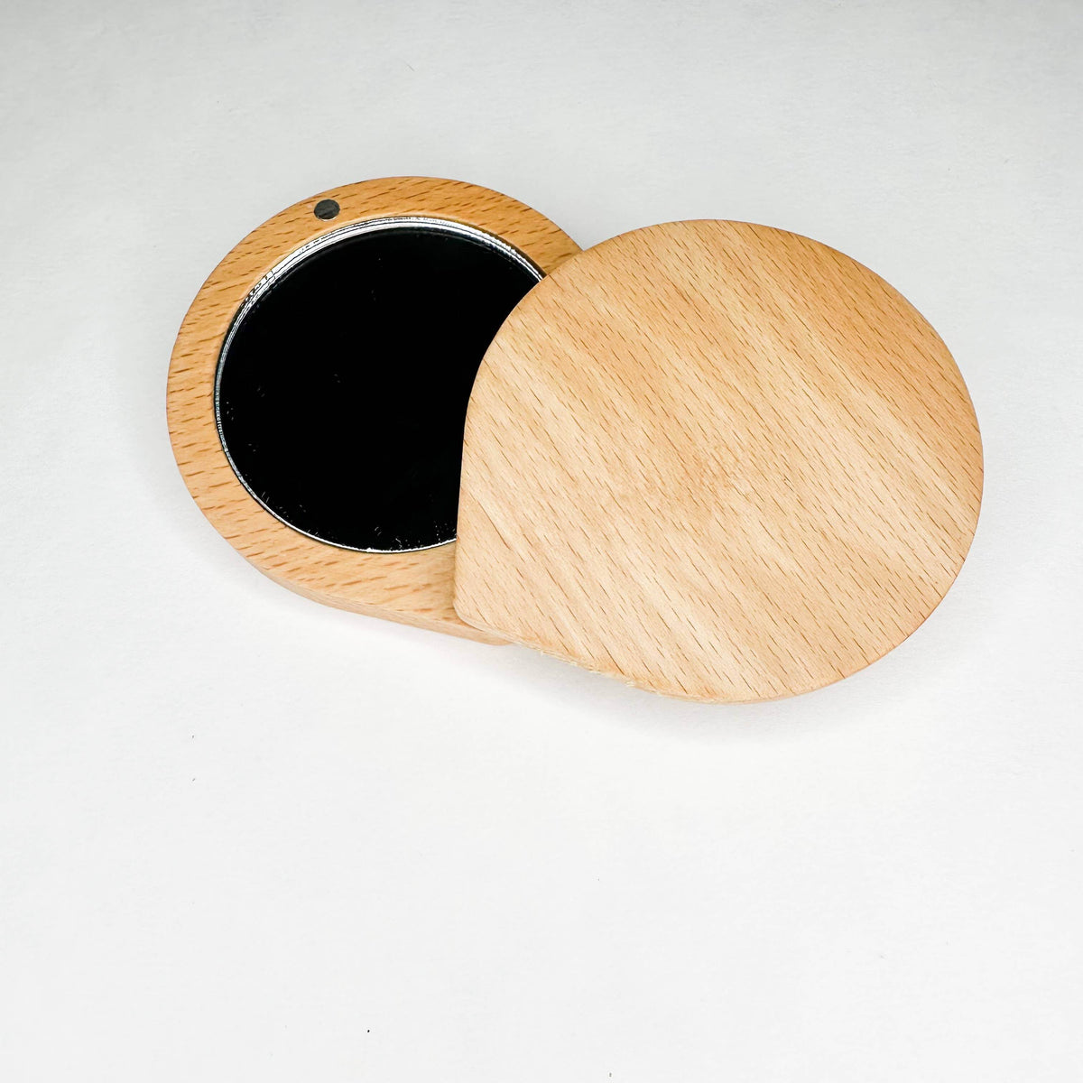 Wooden compact mirror with black interior on a white background