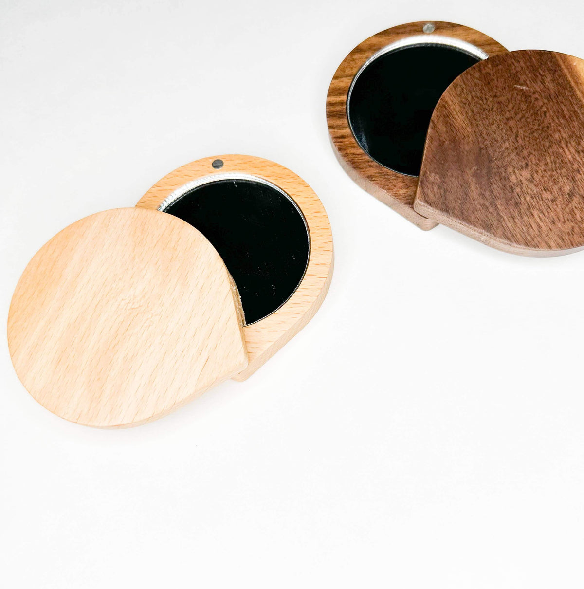 Two wooden compact mirrors on a white background