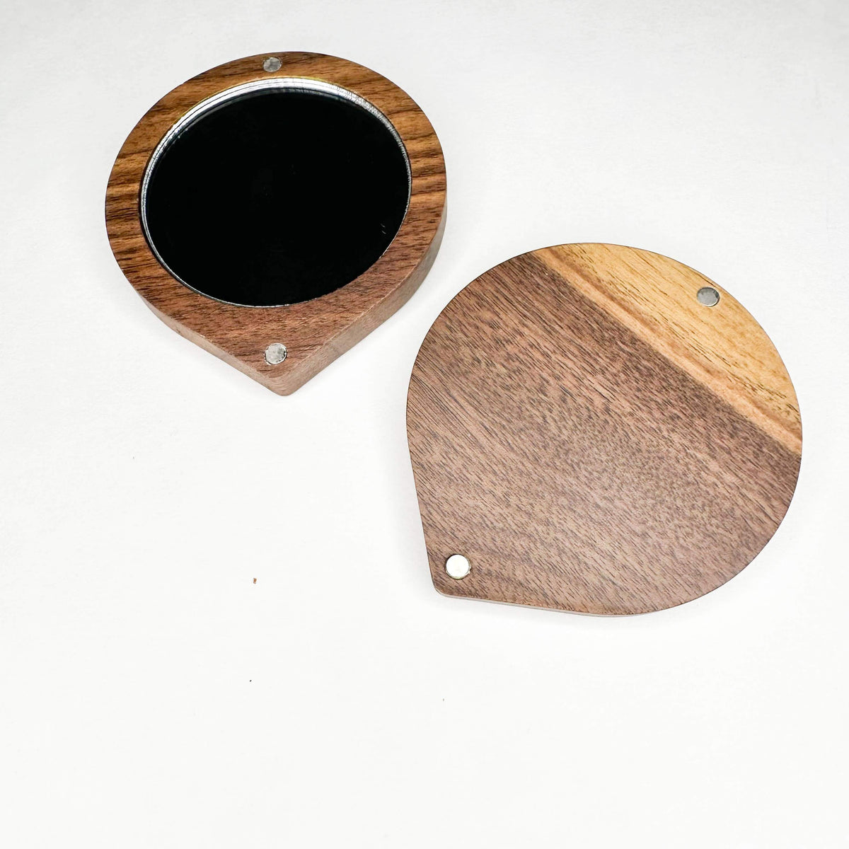 Two wooden coasters with black centers on a white background