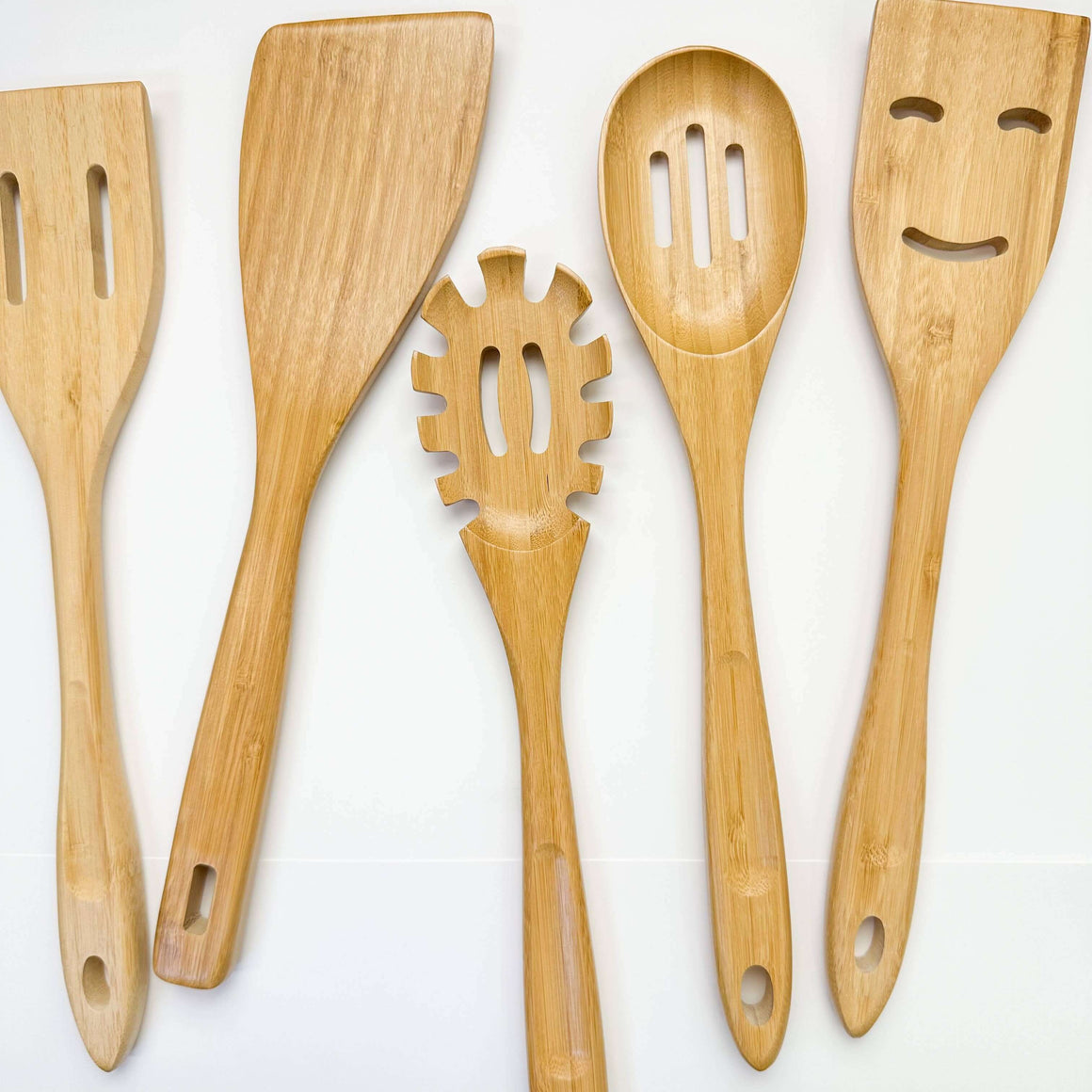 Set of five wooden kitchen utensils with different shapes on a white background