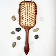 Wooden hairbrush with wooden handle on a white background with stones