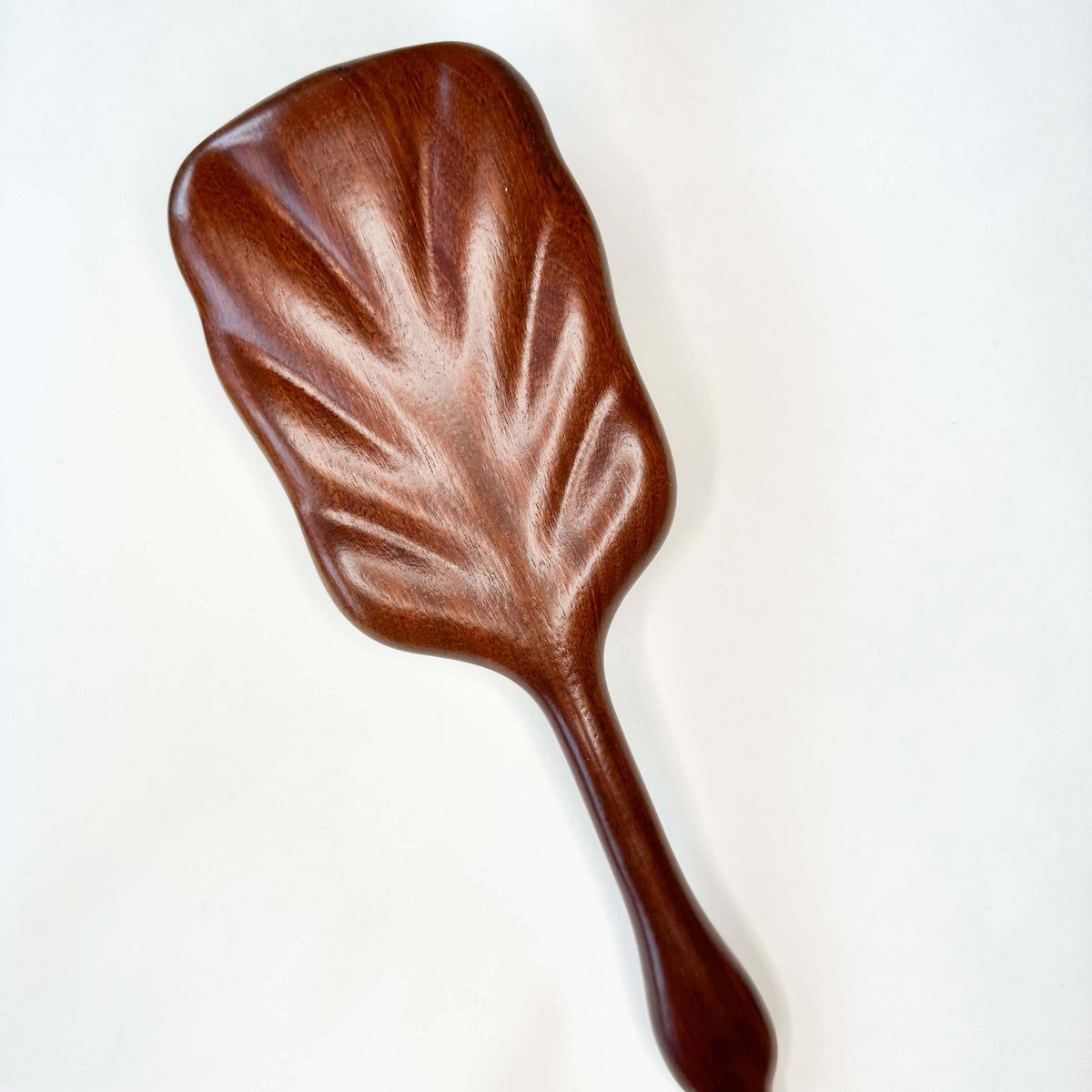 Wooden spoon with a leaf-shaped handle on a white background
