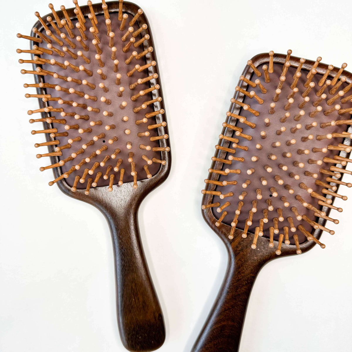 Two wooden hairbrushes with bristle heads on a white background