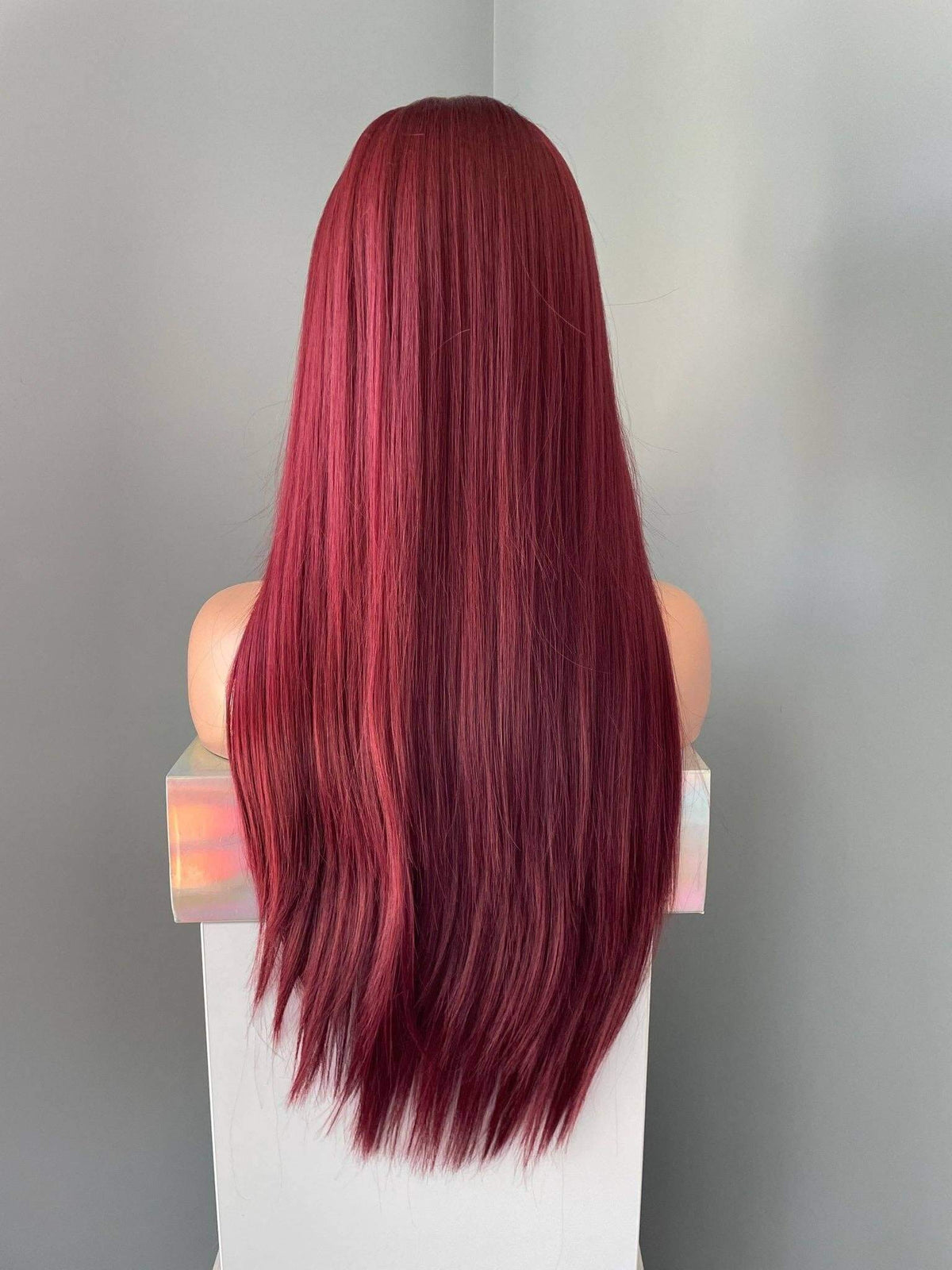 Red wig on a mannequin head against a neutral background