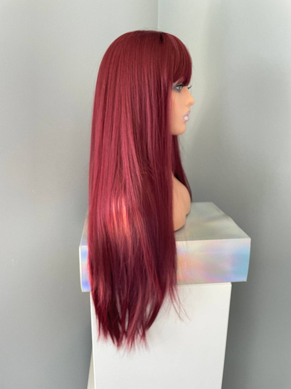 Red wig on a mannequin head against a plain background