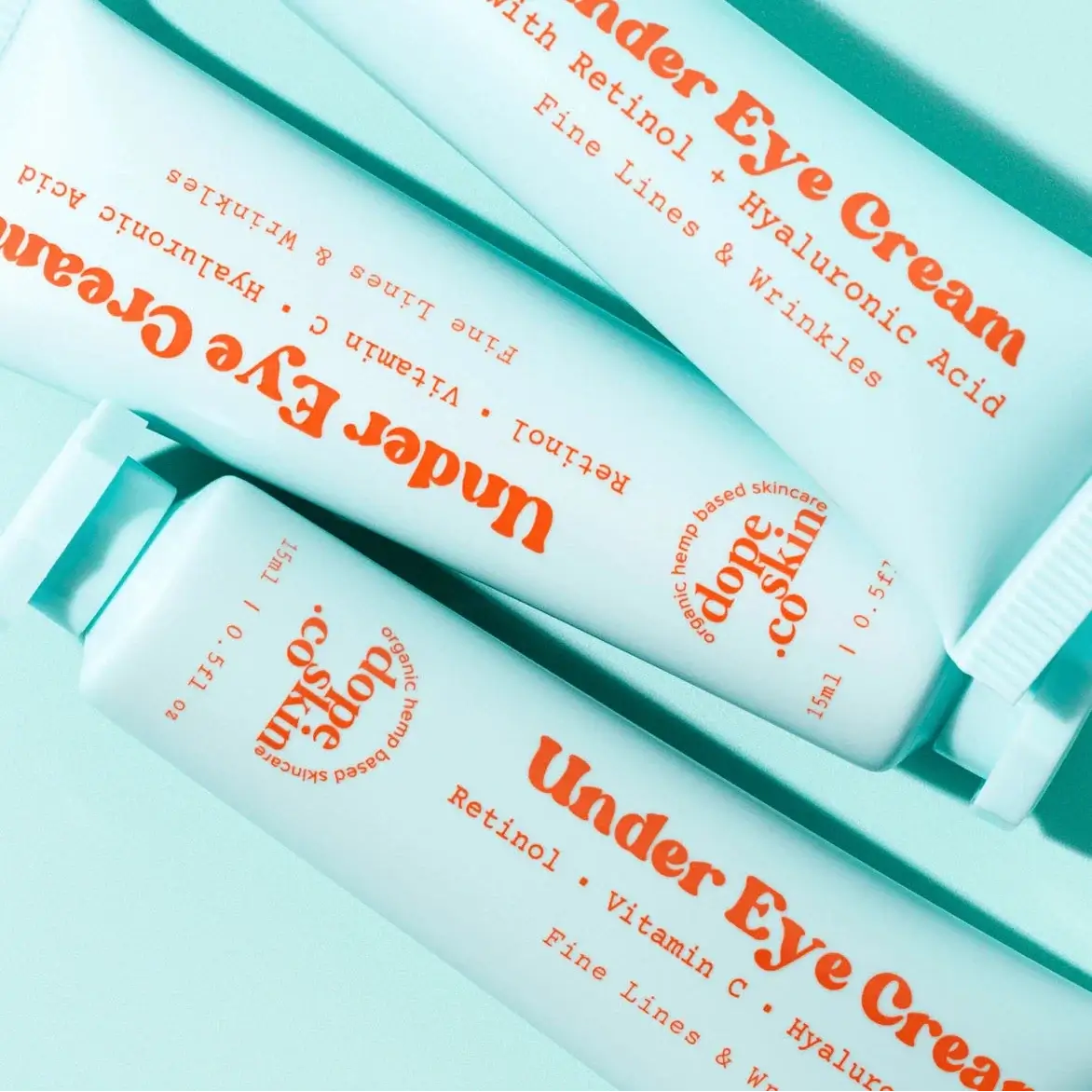 Three bottles of Under Eye Cream with Retinol, Vitamin C, Hyaluronic Acid on a light blue background.