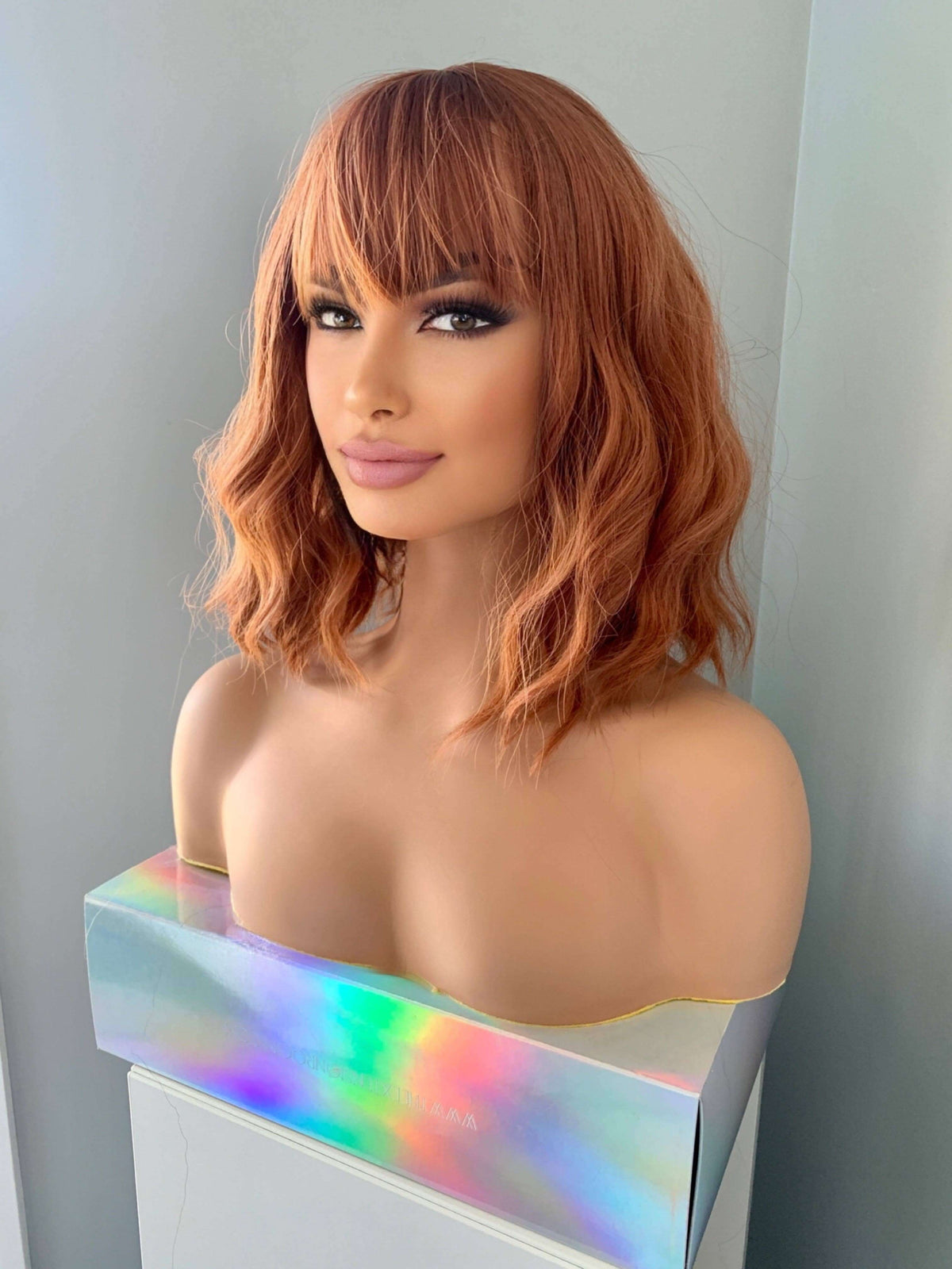 Short auburn body wave wig with bangs displayed on a mannequin, showcasing a chic and modern hairstyle.