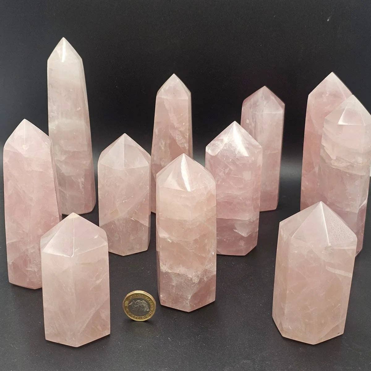 Rose Quartz Crystal Towers arranged artistically with a coin for scale, showcasing their natural beauty and clarity.