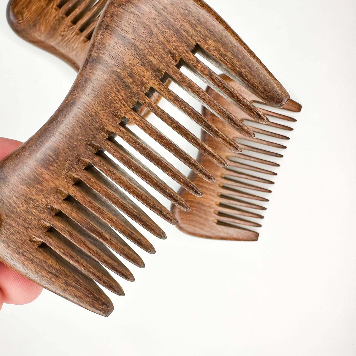 Wooden comb held by a hand on a white background