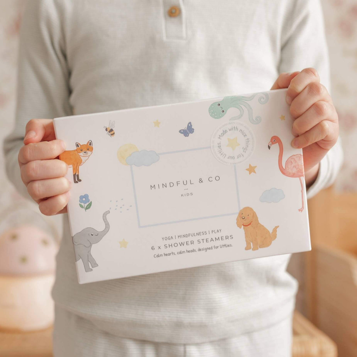 Child holding a box of Sensory Shower Steamers x 6 featuring colorful animal illustrations.