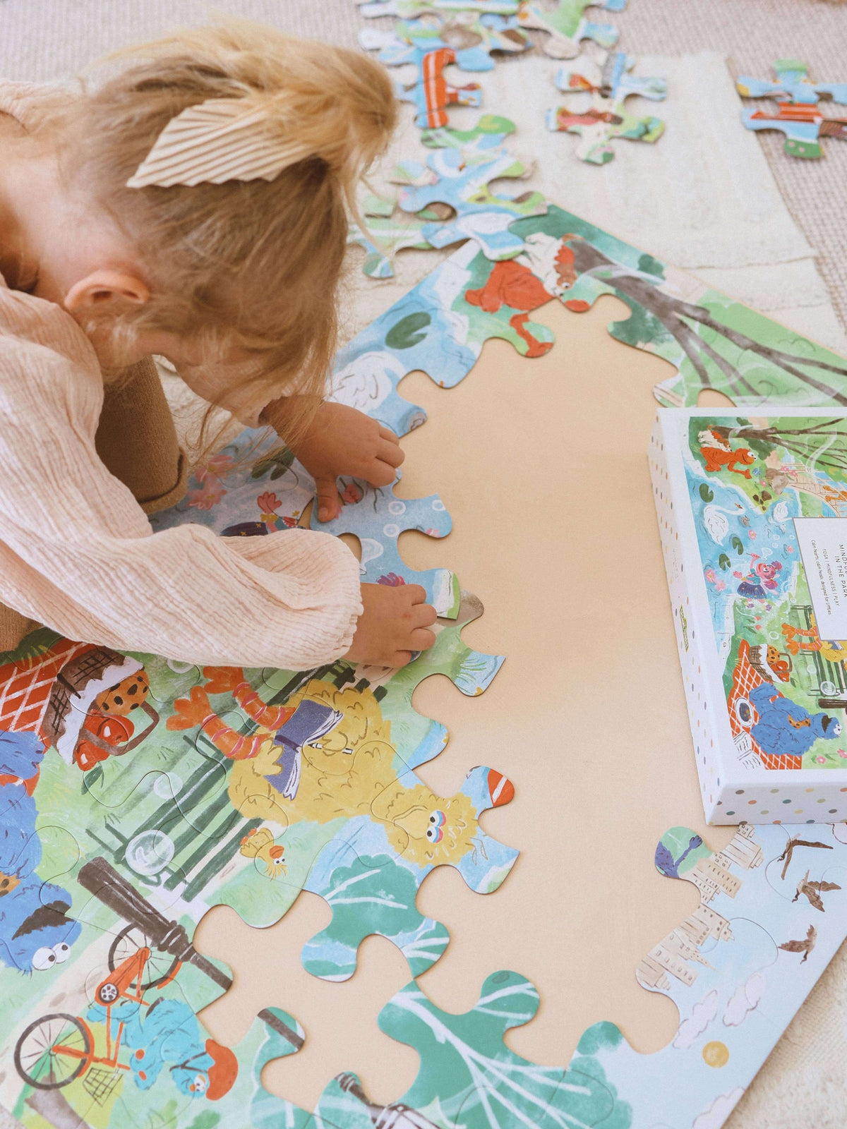 Child playing with Mindful Moments with Sesame Street Floor Puzzle pieces on a colorful mat.