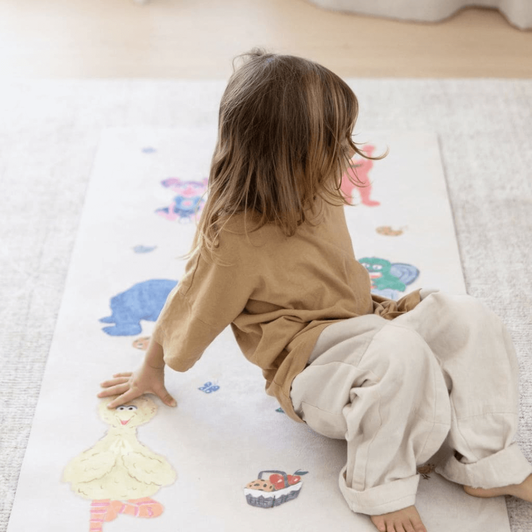 Child practicing yoga on Sesame Street Print Kids Yoga Mat featuring beloved characters in playful poses.