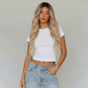 Model wearing Shannon long blonde lace front wig with beach waves and casual white top.