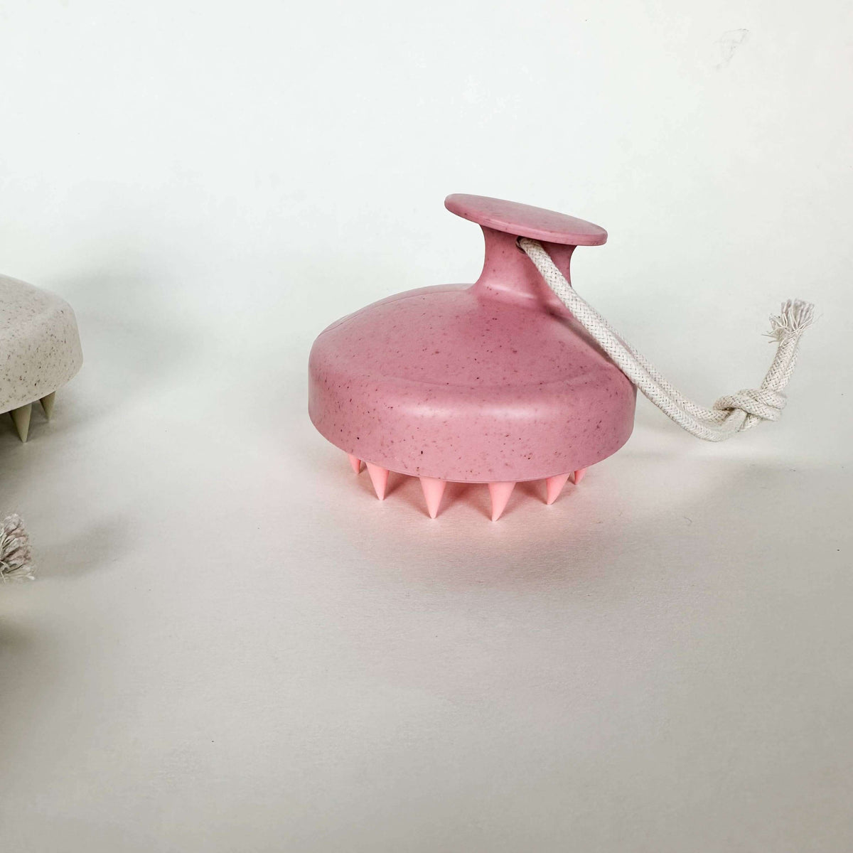 Pink scalp massager with a rope on a white background